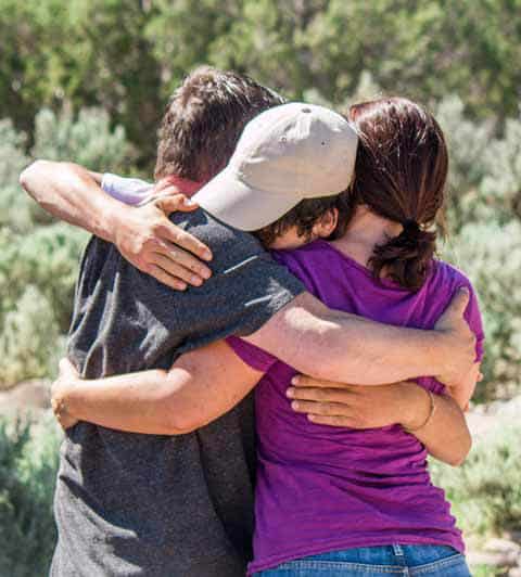 Parents hug their teenage son at a graduation from ThreePeaks Ascent, a nature-based short-term residential treatment center for teens and their families