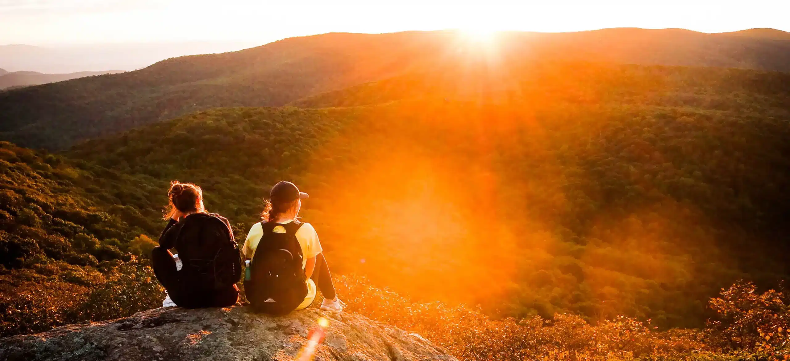 Two teens take a break to watch the sunset while hiking at ThreePeaks Ascent, a nature-based short-term residential treatment program for teens located in southern Utah.
