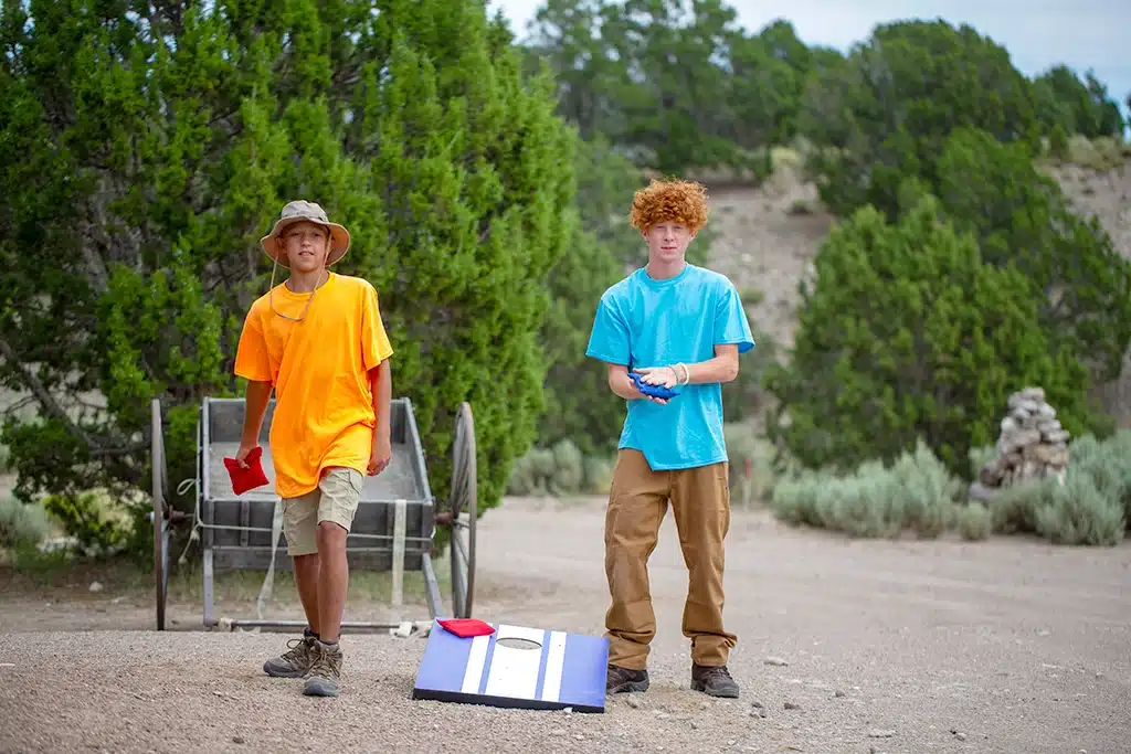 Students play a game of cornhole while attending ThreePeaks Ascent, a nature-based residential program for teens